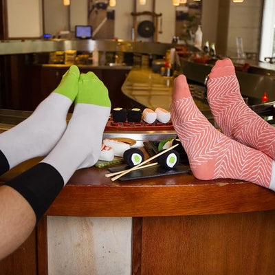 Zwei Personen tragen die Sushi-Socken an einer Sushi-Bar